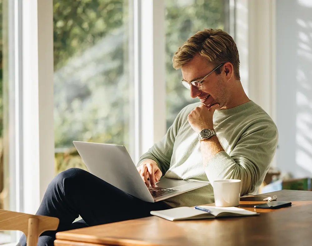 Mann mit Laptop sitzt an einem Schreibtisch